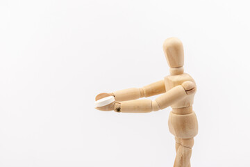 Wooden mannequin with pills on white background. Concept of pharmaceuticals and supplements.