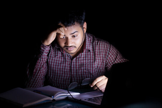 student studying and feeling tensed at mid night in front of a laptop screen