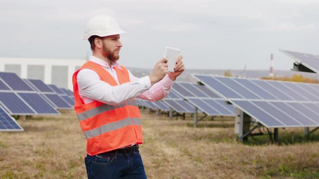 Concept of renewable energy at solar panels farm ecological engineer using digital tablet to controlling the photovoltaic batteries from wireless