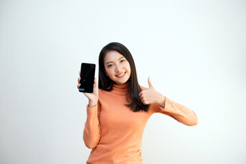 Attractive Asian girl portrait, wearing orange shirt, holding smartphone, smiling face, showing...