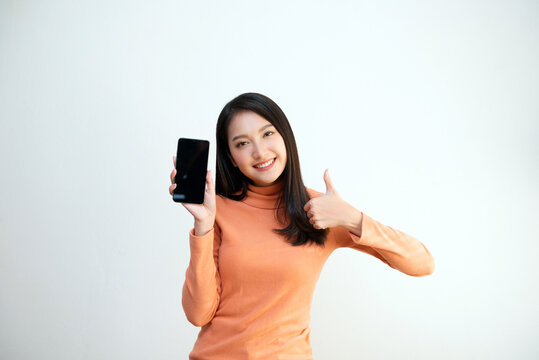 Attractive Asian girl portrait, wearing orange shirt, holding smartphone, smiling face, showing emotion, for communication, advertisement, copy space.