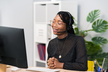 Customer service agent, financial advisor call center employee sits at desk in company in front of computer screen, headphones with microphone on ears, connecting with caller, solving problem