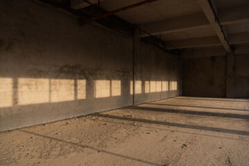 Sunlight shines on the unfinished indoor concrete wall