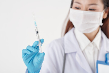 Cropped image of general practitioner looking at syringe with vaccine against coronavirus