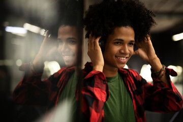 Cheerful guy listening music with the headphones. Young African man enjoying in music.