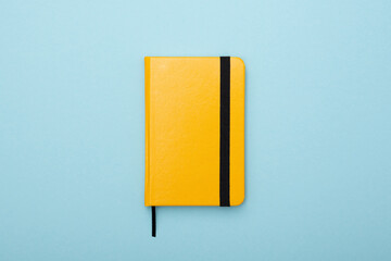 yellow notepad with a black bookmark lies on a blue background. Tool for work and study