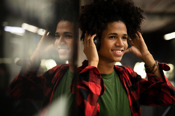 Cheerful guy listening music with the headphones. Young African man enjoying in music.