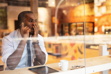 Businessman drinking coffee in cafe. Handsome African man talking to the phone while enjoying in fresh coffee.