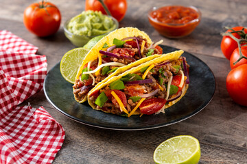 Traditional Mexican tacos with meat and vegetables on wooden table
