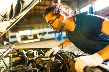 Auto mechanic standing in his workshop in sunset light background