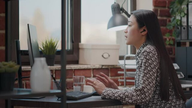 Employee talking to colleague on online video call to do remote business work in office. Person with earpods using video teleconference to chat with worker about project on computer.
