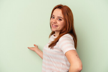 Young caucasian woman isolated on green background showing a welcome expression.