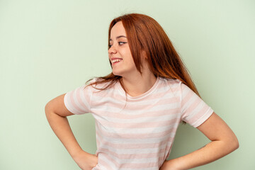 Young caucasian woman isolated on green background laughs happily and has fun keeping hands on...