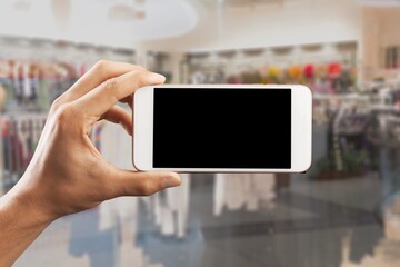 Online shopping concept. Hands holding mobile phone on blurred store as background