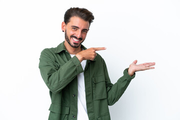 Young caucasian man isolated on white background holding copyspace imaginary on the palm to insert...