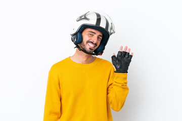 Young caucasian man with a motorcycle helmet isolated on white background saluting with hand with happy expression