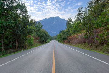 Fototapeta premium Empty road or street to Doi Luang Chiang Dao, Chiang Mai on mountain hill with green natural forest trees in rural area, Thailand. Transportation. Nature landscape background