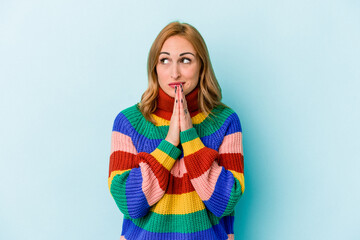 Young caucasian woman isolated on blue background praying, showing devotion, religious person...