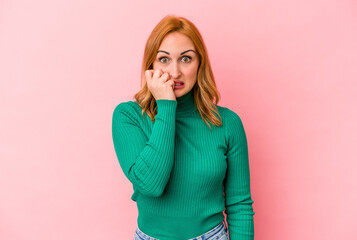 Young caucasian woman isolated on pink background biting fingernails, nervous and very anxious.