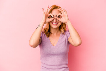 Young caucasian woman isolated on pink background excited keeping ok gesture on eye.