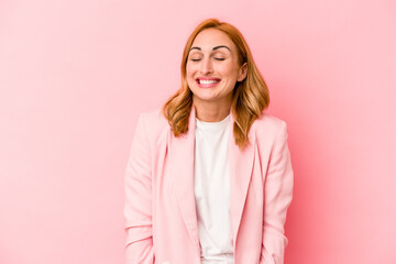 Fototapeta premium Young caucasian woman isolated on pink background laughs and closes eyes, feels relaxed and happy.