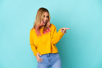 Young woman over isolated blue background pointing finger to the side and presenting a product