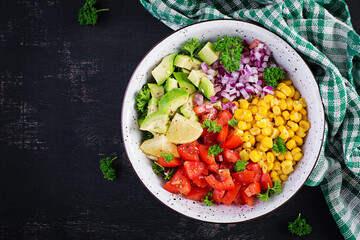 Salad with avocado, tomatoes, red onions and sweet corn in bowl. Vegetarian buddha bowl. Vegan food. Top view, flat lay