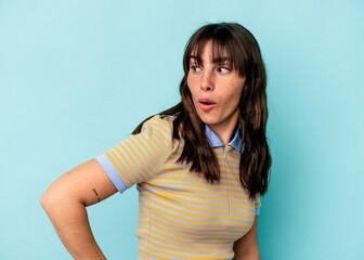 Young Argentinian woman isolated on blue background looks aside smiling, cheerful and pleasant.
