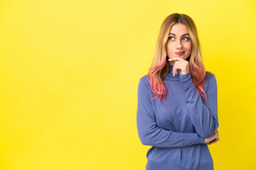 Young woman over isolated yellow background having doubts and thinking