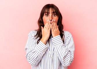 Young Argentinian woman isolated on pink background shocked covering mouth with hands.