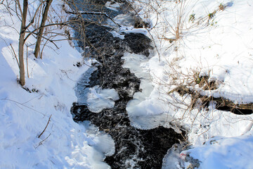 Winter park and stream under ice and snow