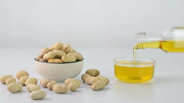 Pouring peanut oil also known as groundnut oil in a cup