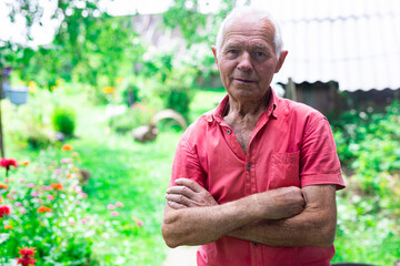 senior pensioner in red polo posing near the house in the village