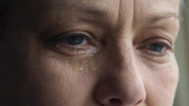 Close-up of a mature crying woman, tears flowing from her eyes.