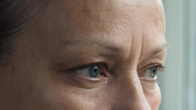 Close-up of a mature woman's eye, she looks into the distance, blinks