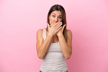 Middle age caucasian woman isolated on pink background covering mouth with hands