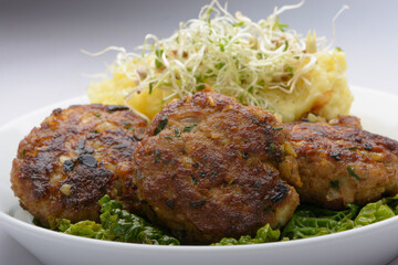 studio shot of meatballs with mashed potatoes and bean sprouts as decoration against a white background