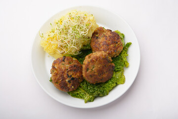 studio shot of meatballs with mashed potatoes and bean sprouts as decoration against a white background