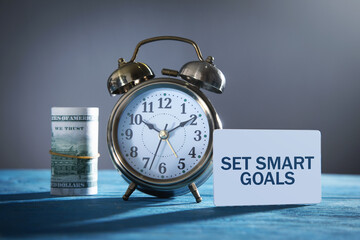 Paper with text Set Smart Goals and money, alarm clock.