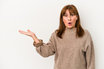 Middle age caucasian woman isolated on white background impressed holding copy space on palm.