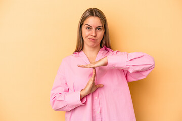 Young caucasian woman isolated on yellow background showing a timeout gesture.