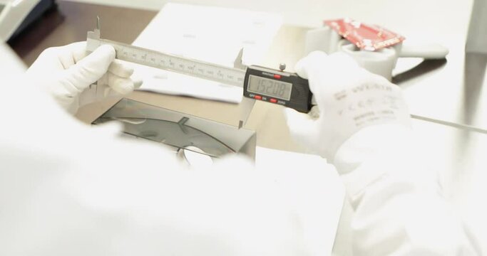 Worker Measuring Plastic Part With Digital Caliper. close up