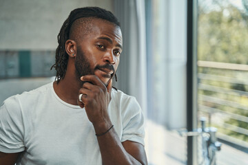 Man touching his beard with one hand before mirror