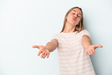 Young caucasian woman isolated on blue background folding lips and holding palms to send air kiss.