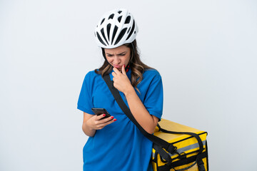 Young delivery woman with thermal backpack isolated on white background thinking and sending a message