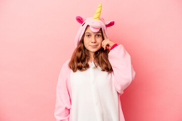 Little caucasian girl wearing a unicorn pajama isolated on pink background pointing temple with finger, thinking, focused on a task.