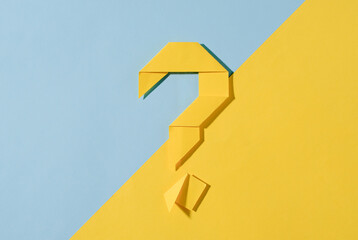 Yellow origami question mark on a diagonal two tone background