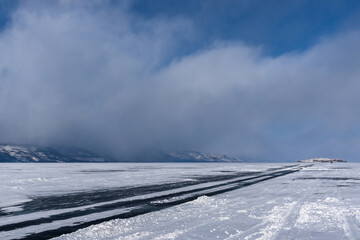 Winter road on the ice of Lake Baikal near Olkhon Island on a cloudy day