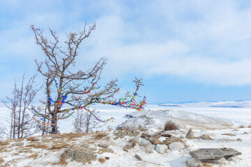 Winter landscape. A ritual site at the top of Ogoy Island. View of the mountains and frozen Lake Baikal on a winter day - 472030834