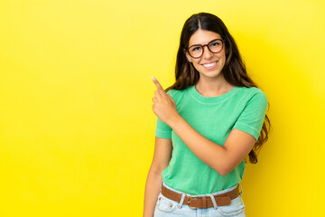 Young caucasian woman isolated on yellow background pointing to the side to present a product